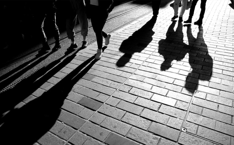 Silhouettes en pantalon marchant sur des pavés